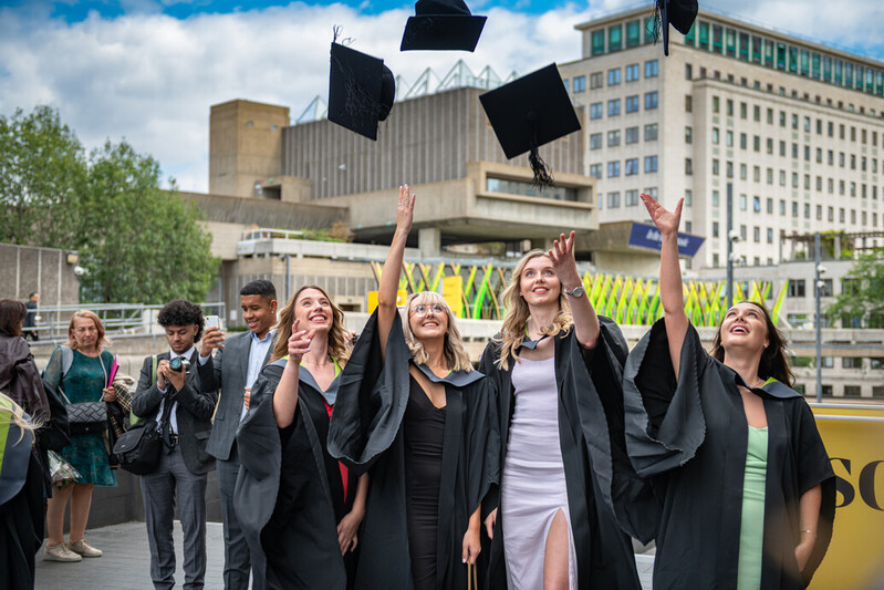 A group of four students throw their graduation caps in the air